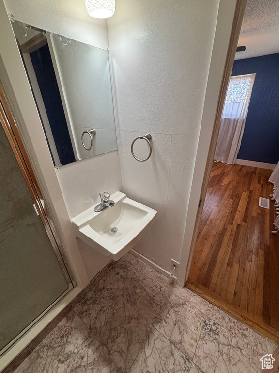 Bathroom with visible vents, a shower stall, wood finished floors, a textured ceiling, and a sink