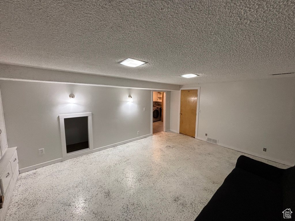 Unfurnished room featuring visible vents, a textured ceiling, washer / clothes dryer, and speckled floor