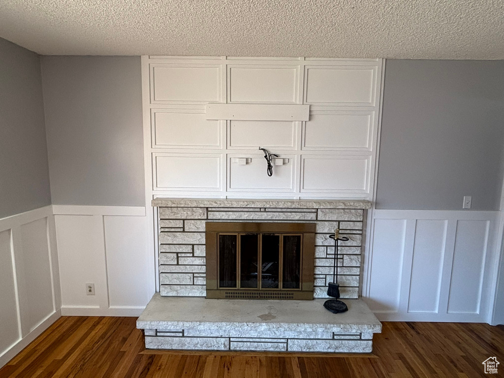 Room details with wood finished floors, a decorative wall, a fireplace, and a textured ceiling