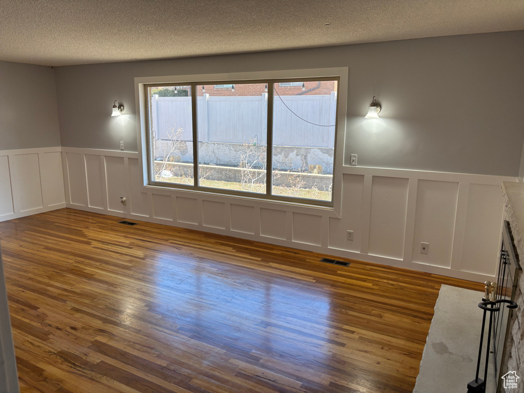Empty room featuring visible vents, a textured ceiling, wood finished floors, and a fireplace