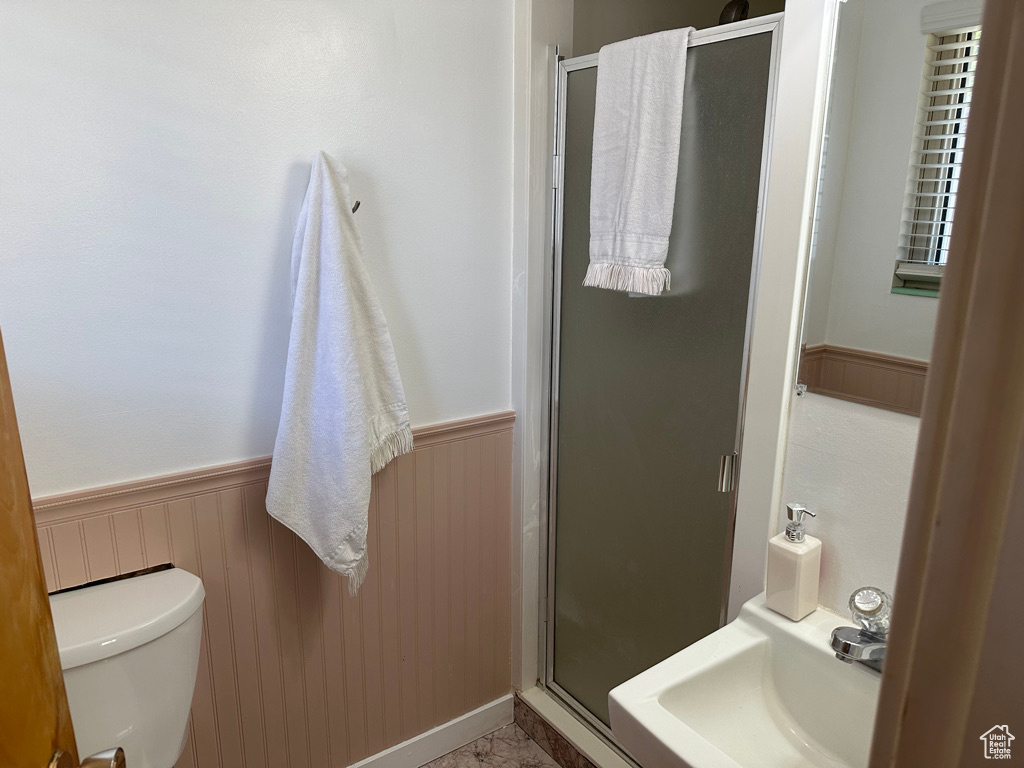 Bathroom featuring wainscoting, a shower stall, toilet, and a sink