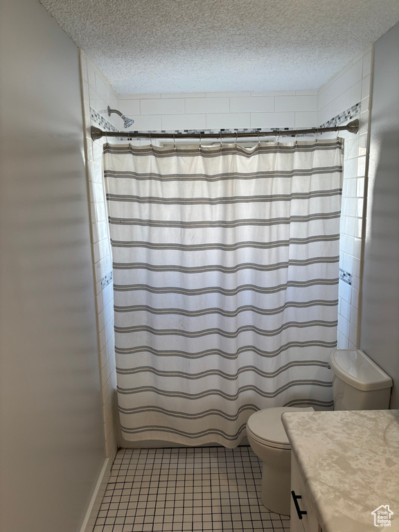 Full bath featuring curtained shower, a textured ceiling, and toilet