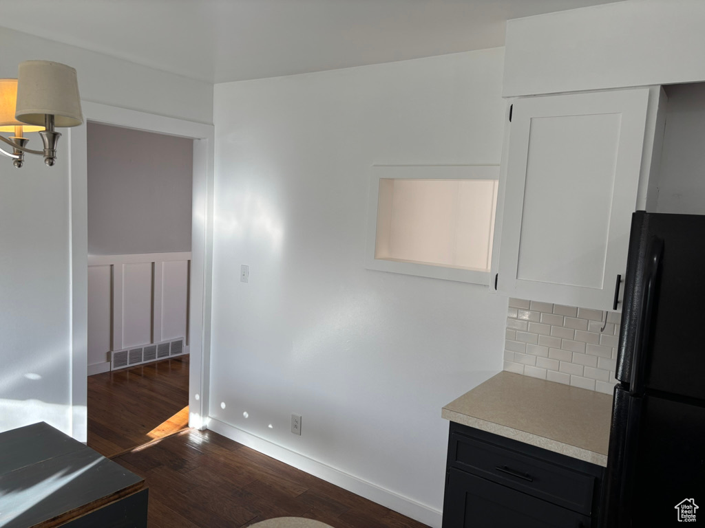 Interior space with visible vents, dark wood finished floors, freestanding refrigerator, light countertops, and tasteful backsplash