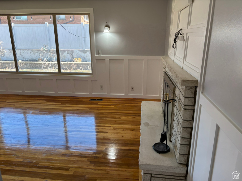 Interior space with a wealth of natural light, visible vents, wood finished floors, and a decorative wall