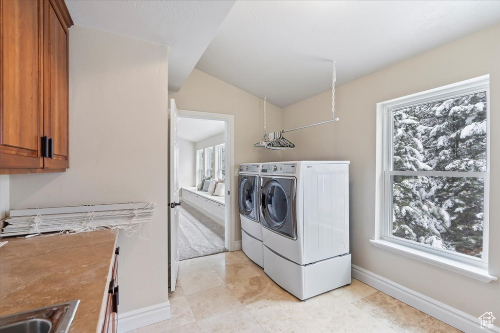 Laundry area with cabinet space, washing machine and dryer, a healthy amount of sunlight, and a sink