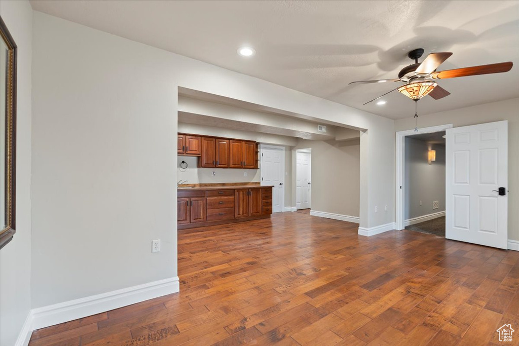 Unfurnished living room featuring a ceiling fan, dark wood-type flooring, recessed lighting, and baseboards