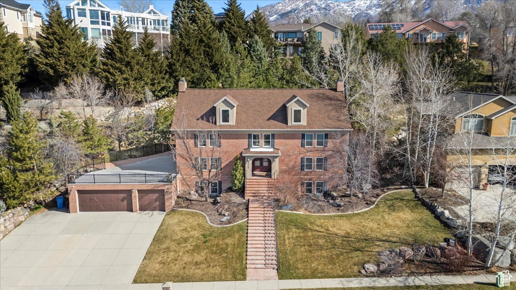 View of front of house featuring brick siding, driveway, a chimney, and a front yard