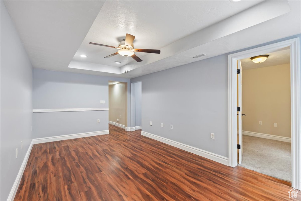 Unfurnished room featuring ceiling fan, baseboards, a raised ceiling, and wood finished floors