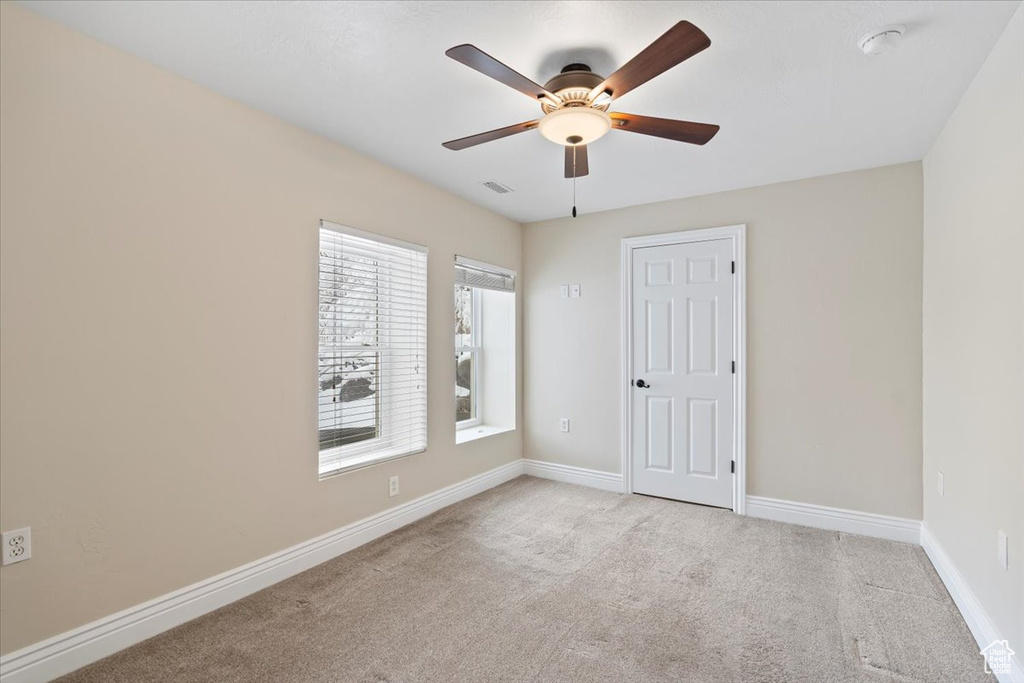 Carpeted spare room with visible vents, baseboards, and ceiling fan