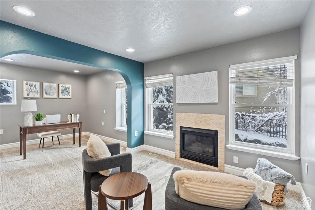 Living area with arched walkways, a glass covered fireplace, recessed lighting, and baseboards