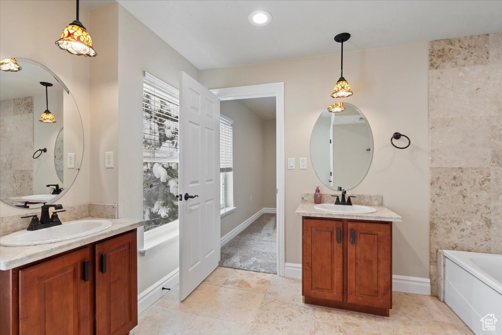 Bathroom featuring tile patterned floors, a washtub, two vanities, and a sink
