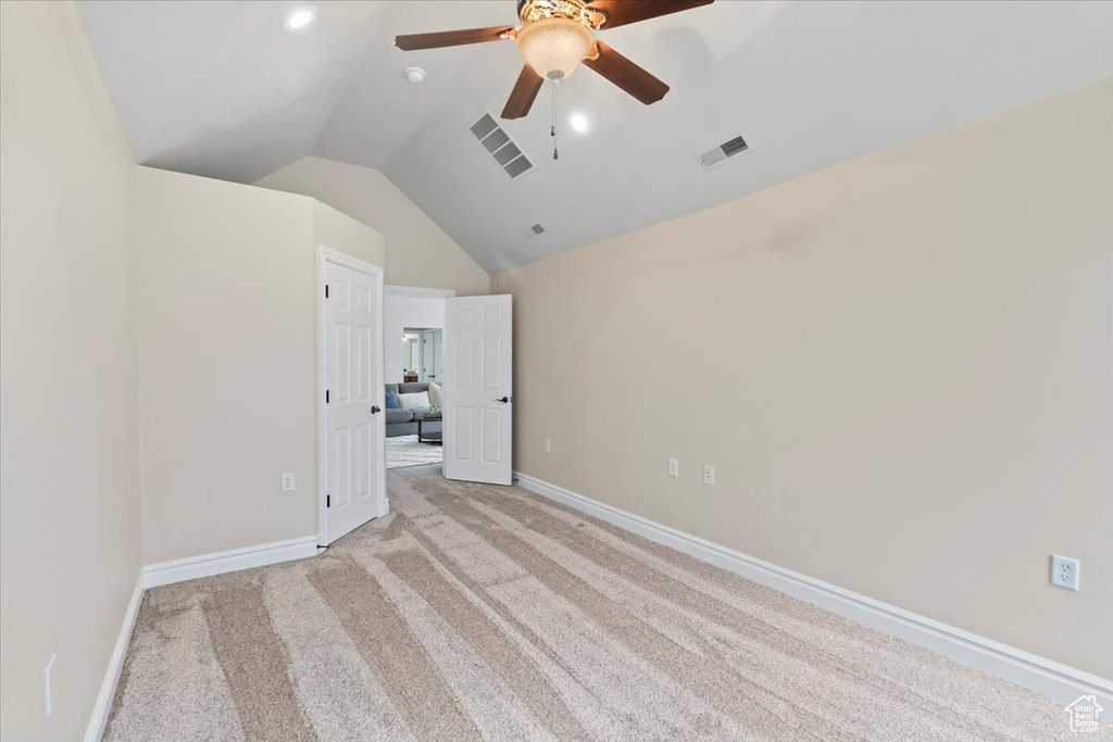 Unfurnished room with visible vents, baseboards, light carpet, and vaulted ceiling