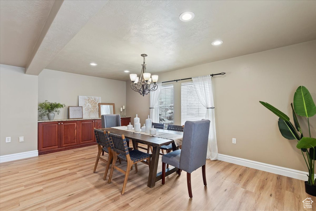 Dining area with light wood-type flooring, a textured ceiling, recessed lighting, baseboards, and a chandelier
