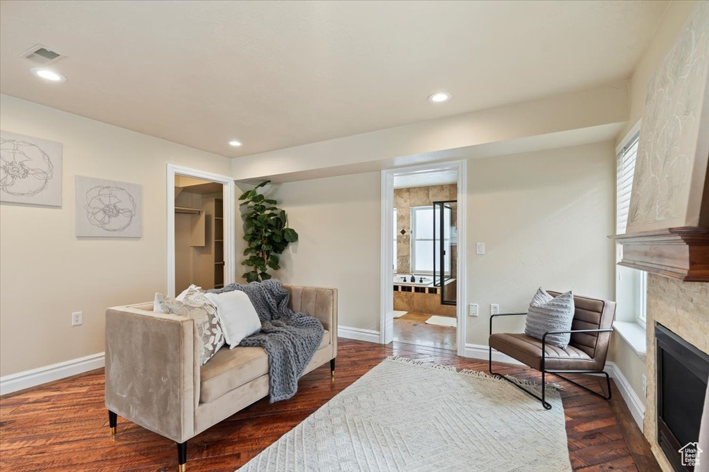 Living room with visible vents, dark wood-style flooring, baseboards, and a glass covered fireplace