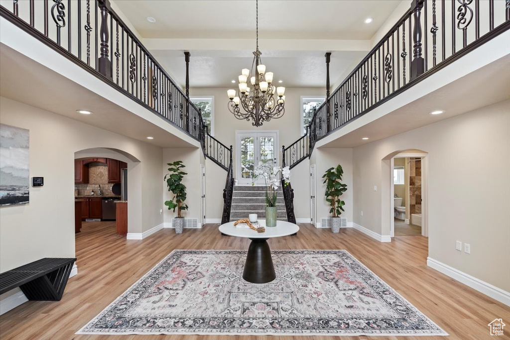 Entrance foyer featuring wood finished floors, arched walkways, baseboards, a towering ceiling, and stairs