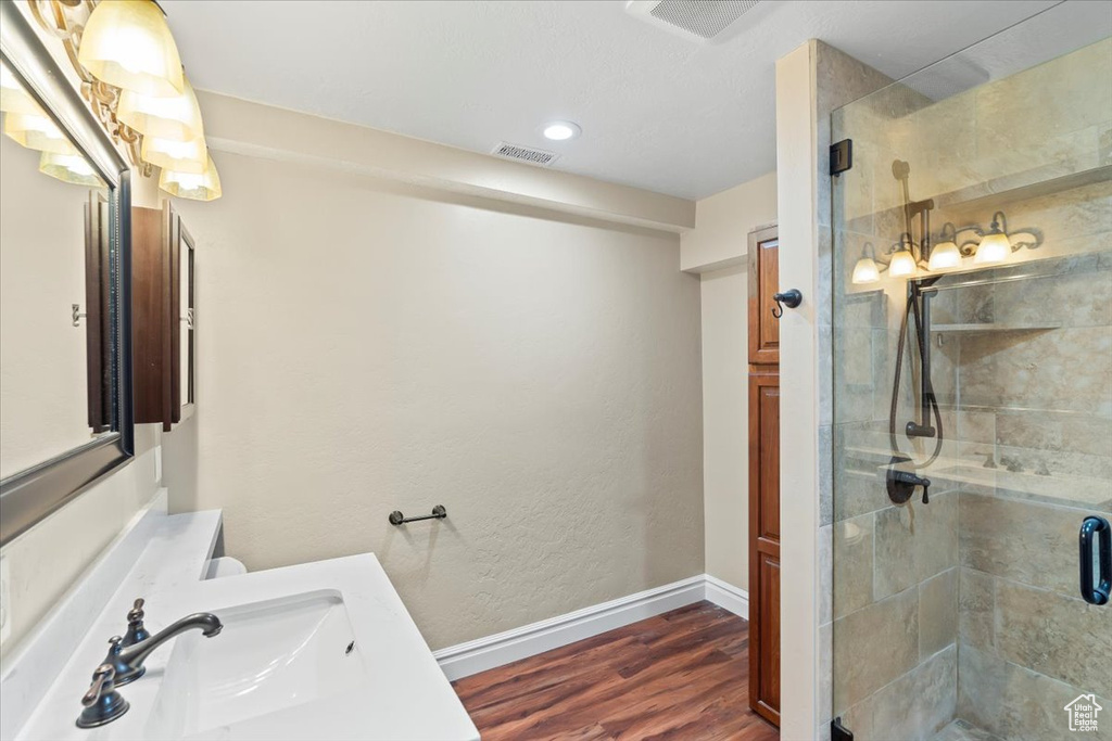 Full bathroom featuring baseboards, wood finished floors, visible vents, and a stall shower