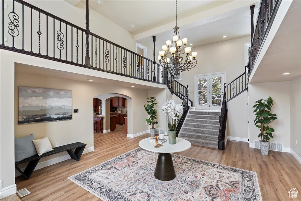 Entrance foyer with wood finished floors, arched walkways, a high ceiling, baseboards, and stairs