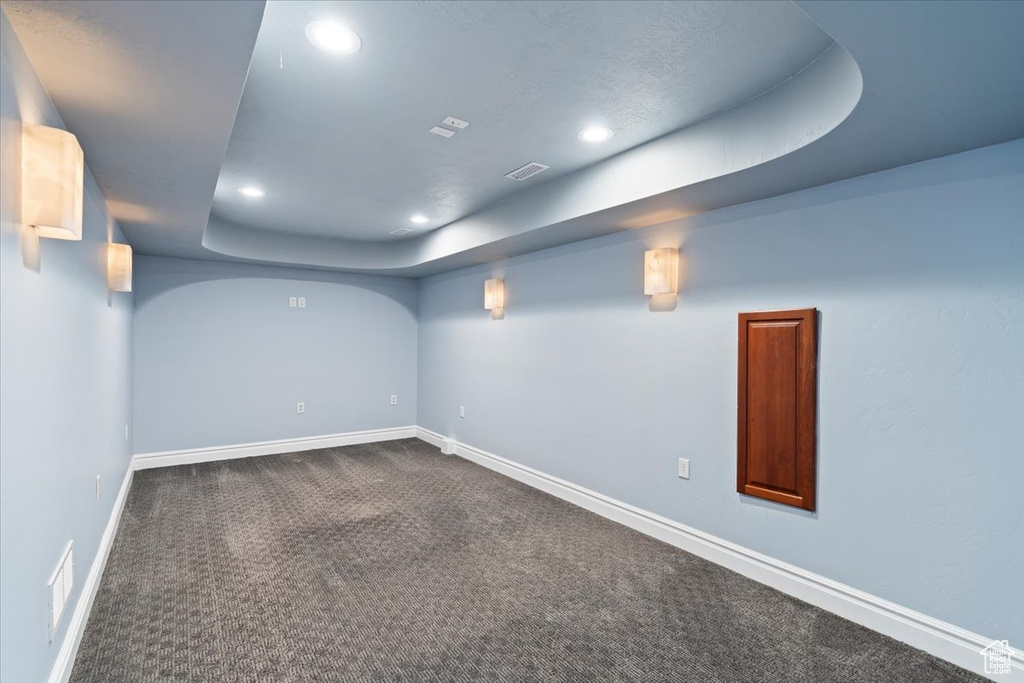 Below grade area with dark colored carpet, visible vents, baseboards, and recessed lighting
