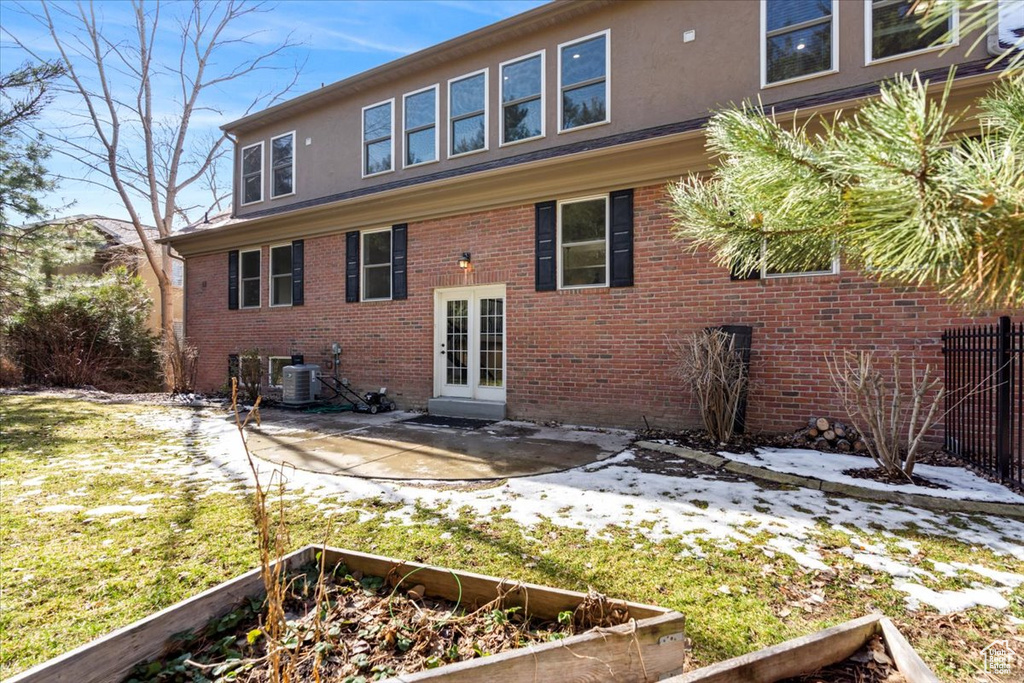 Back of house with stucco siding, french doors, a vegetable garden, brick siding, and a patio area