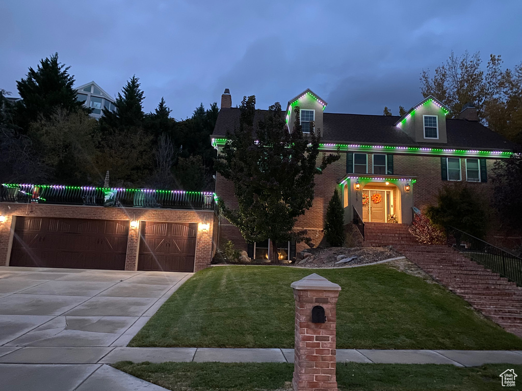 View of front of home featuring brick siding, a front yard, concrete driveway, and a garage