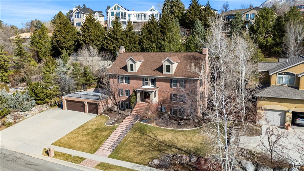 View of front of house with a front yard, a garage, driveway, and a chimney