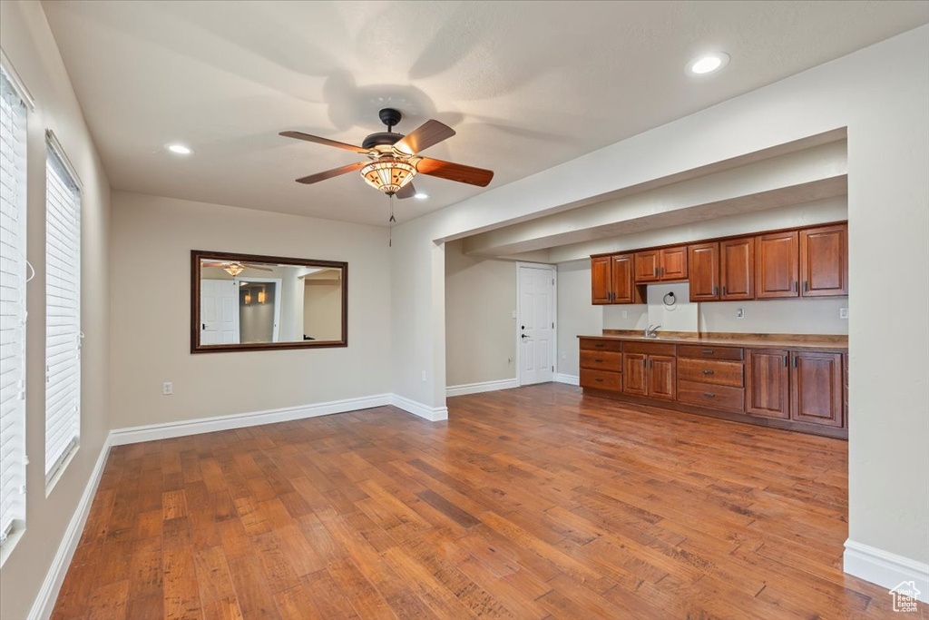 Kitchen with recessed lighting, brown cabinetry, dark wood-style flooring, and baseboards