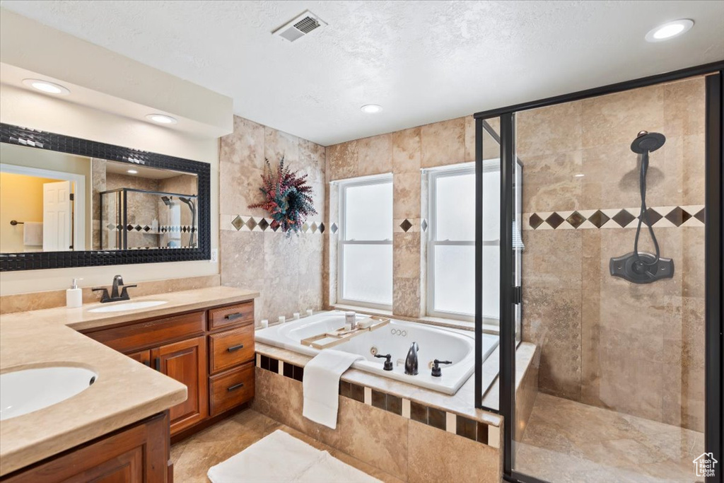Bathroom featuring visible vents, a textured ceiling, a jetted tub, a shower stall, and vanity