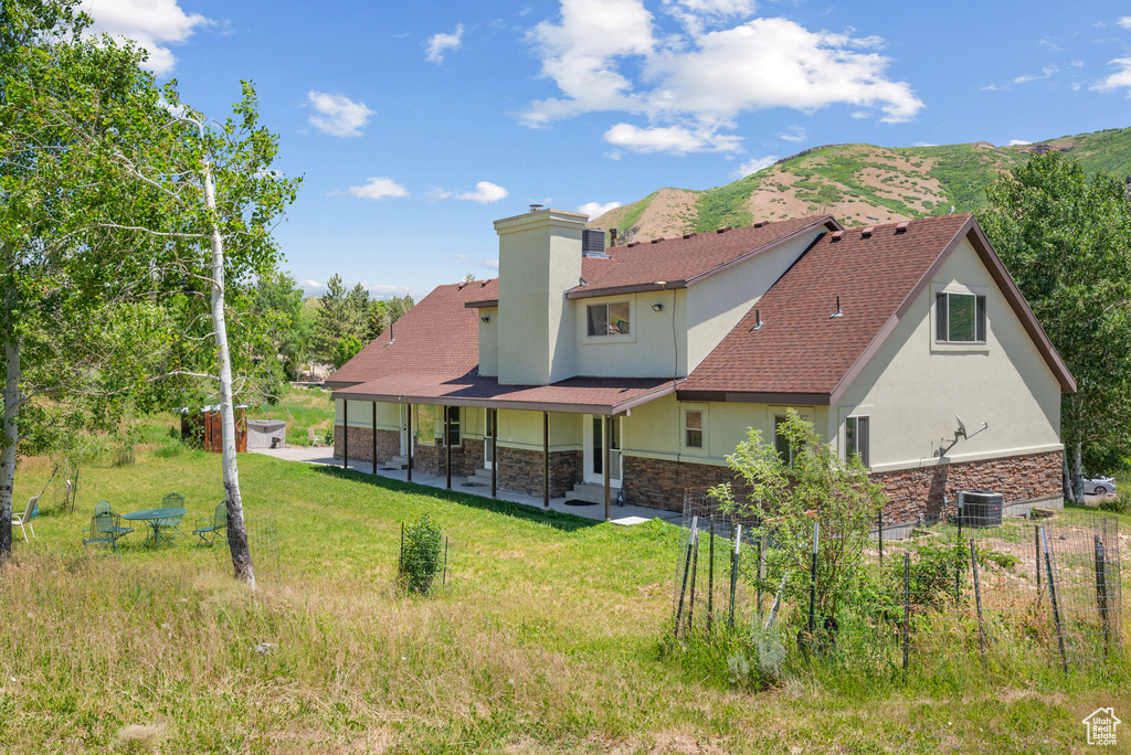 Rear view of property with stucco siding, stone siding, a patio, and a chimney