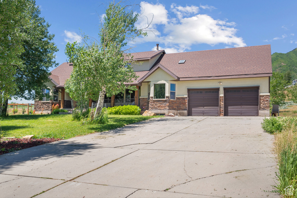 View of front of house with stucco siding, stone siding, and driveway