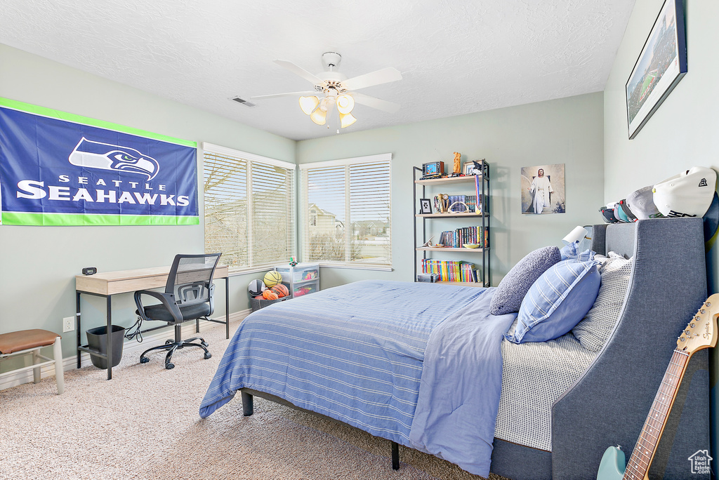 Bedroom featuring visible vents, baseboards, carpet floors, a textured ceiling, and a ceiling fan