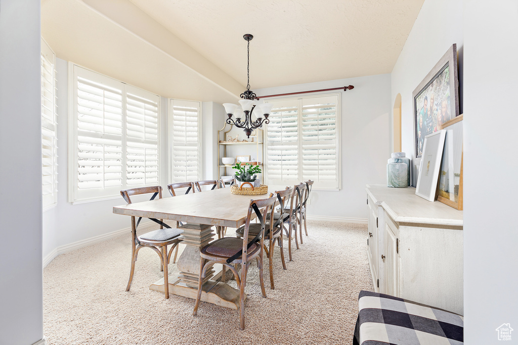 Dining area featuring a notable chandelier, baseboards, and light colored carpet