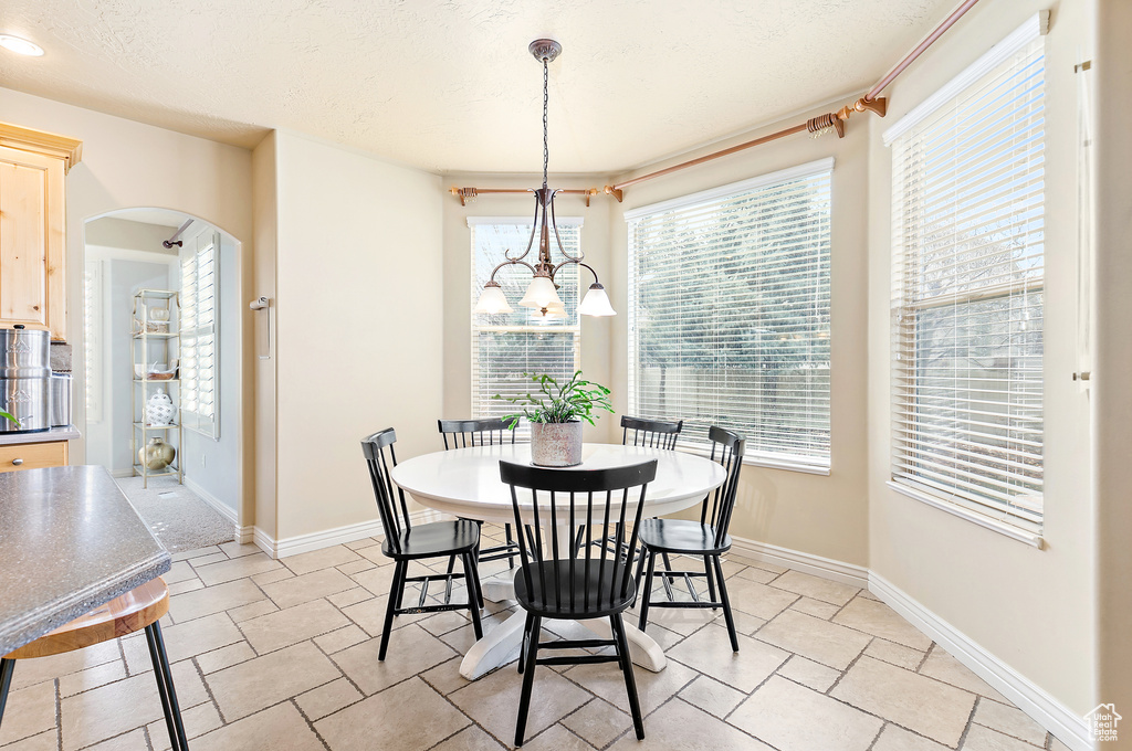 Dining room with stone finish flooring, baseboards, arched walkways, and a textured ceiling