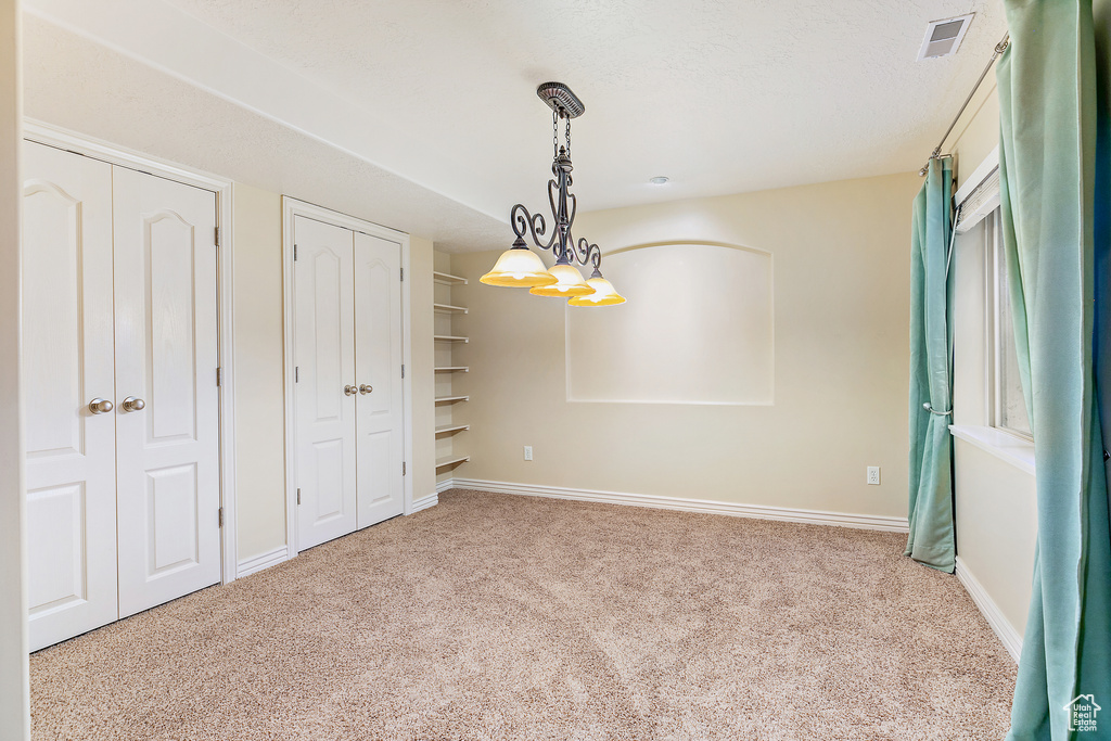 Unfurnished bedroom featuring visible vents, a textured ceiling, baseboards, and carpet floors