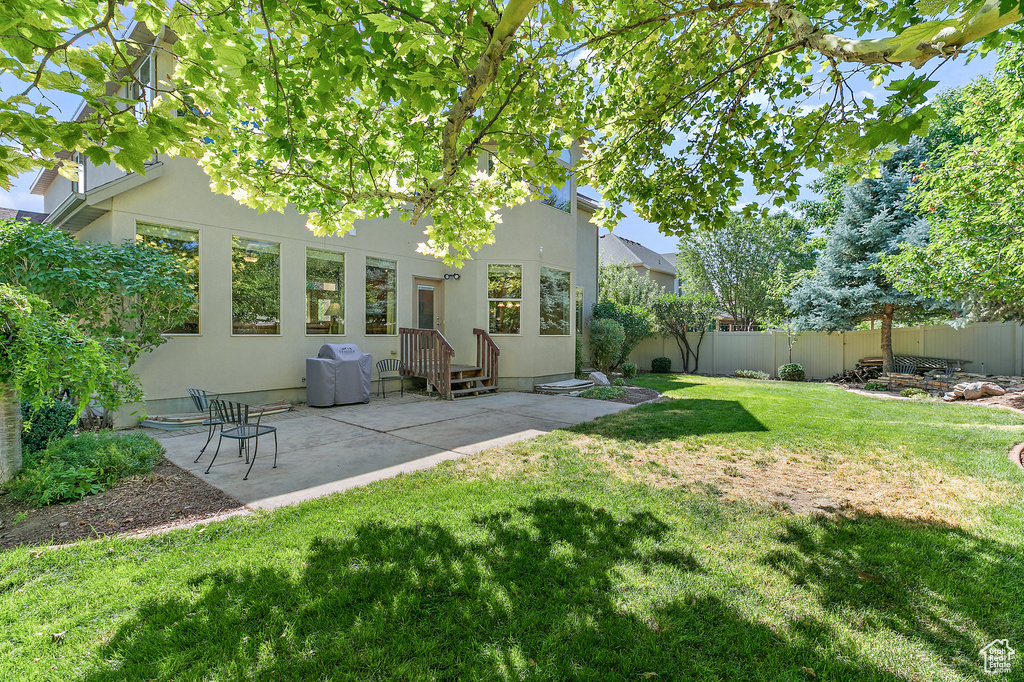 Rear view of property featuring a patio area, stucco siding, a yard, and fence