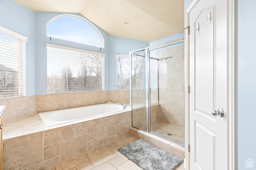 Full bath featuring a bath, a stall shower, a textured ceiling, and vaulted ceiling