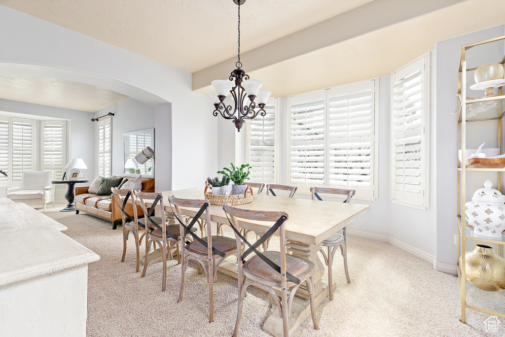 Dining area with a notable chandelier, baseboards, and arched walkways