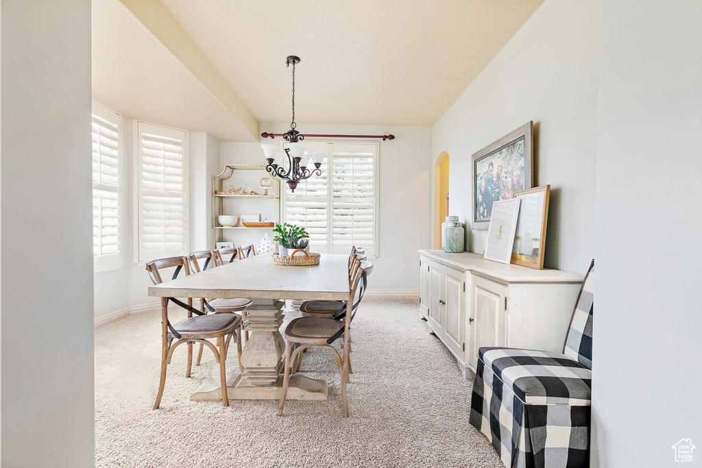 Dining area featuring a wealth of natural light, baseboards, light colored carpet, and a chandelier