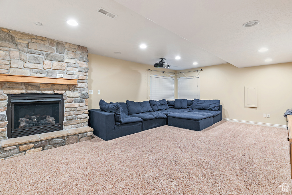 Carpeted living area with recessed lighting, visible vents, baseboards, and a stone fireplace