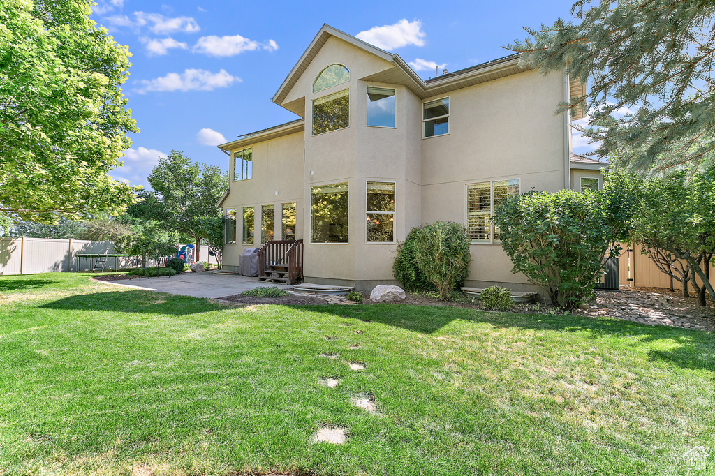 Back of house with a patio area, a yard, fence, and stucco siding