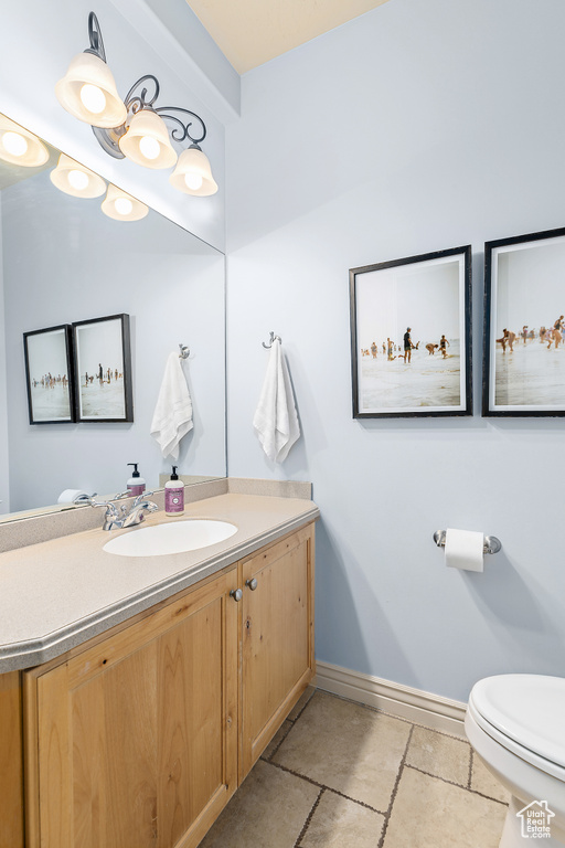 Half bathroom featuring baseboards, toilet, and vanity