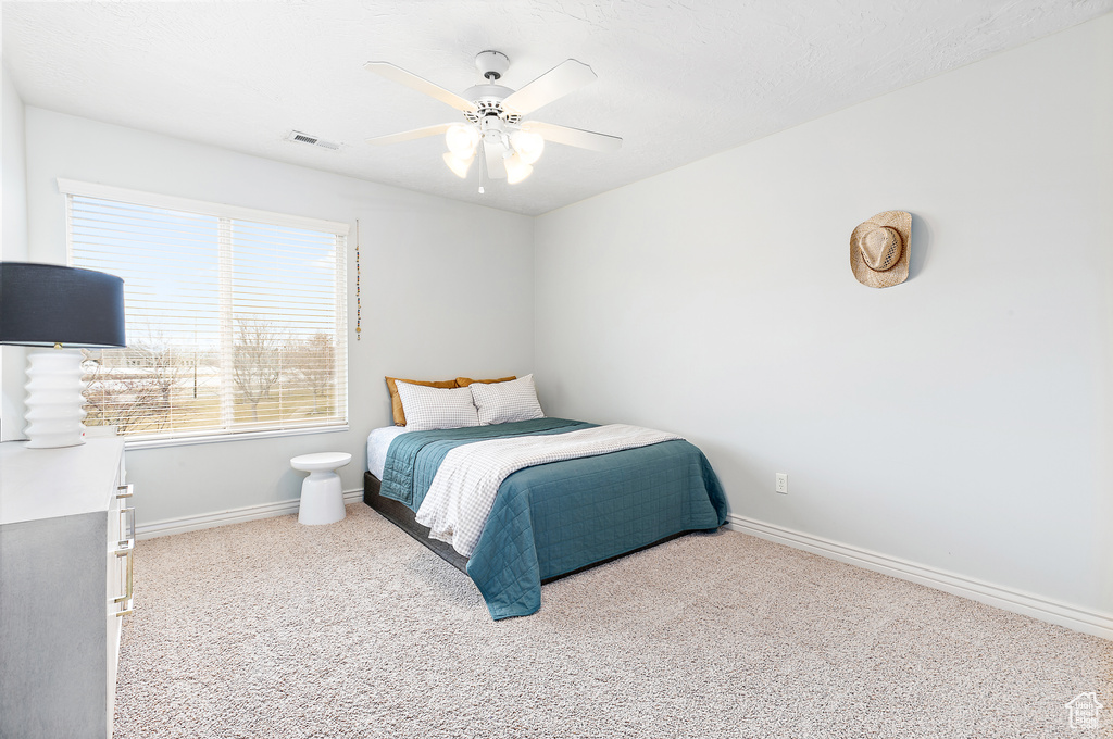 Carpeted bedroom featuring visible vents, baseboards, and a ceiling fan