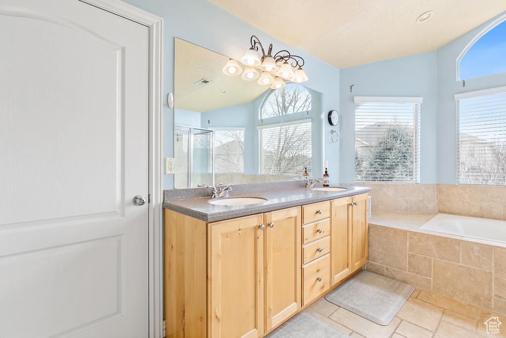 Full bath with double vanity, vaulted ceiling, visible vents, and a sink