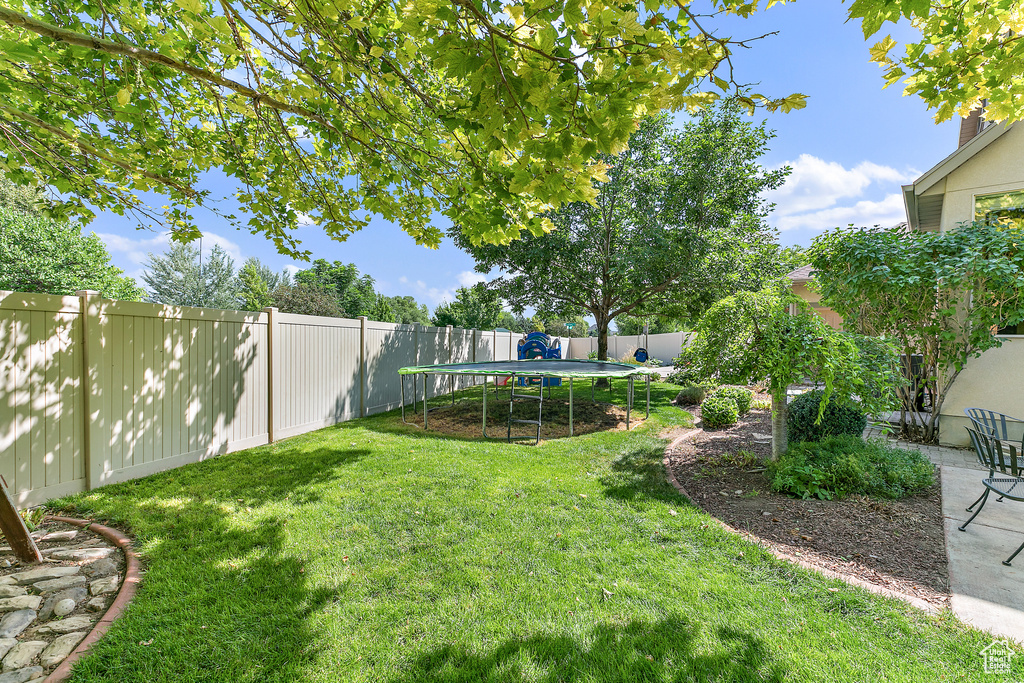 View of yard featuring a fenced backyard, a patio area, and a trampoline