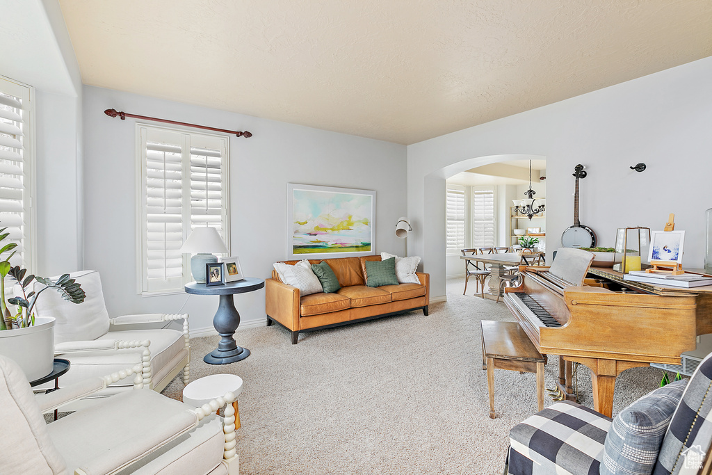 Carpeted living room with baseboards, arched walkways, and a healthy amount of sunlight