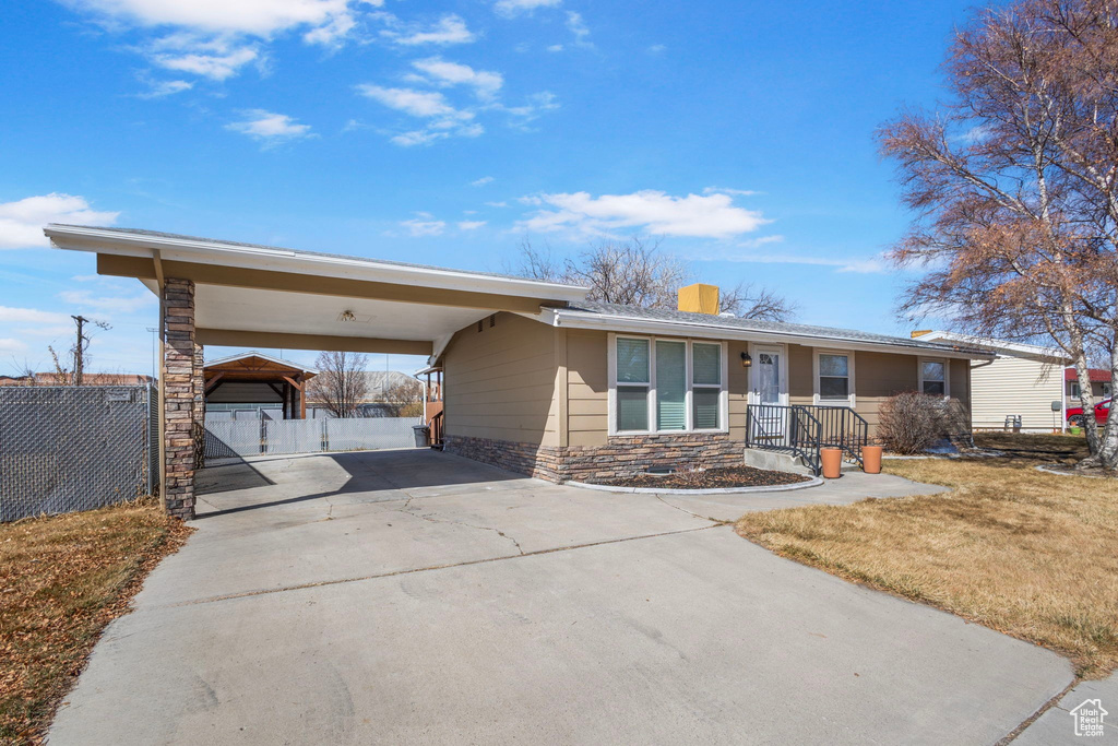 Ranch-style home with a front lawn, driveway, and fence