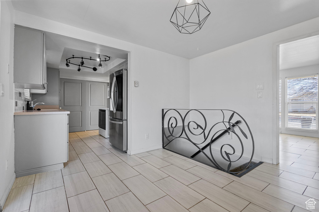 Kitchen with track lighting, smart refrigerator, range, light countertops, and baseboards