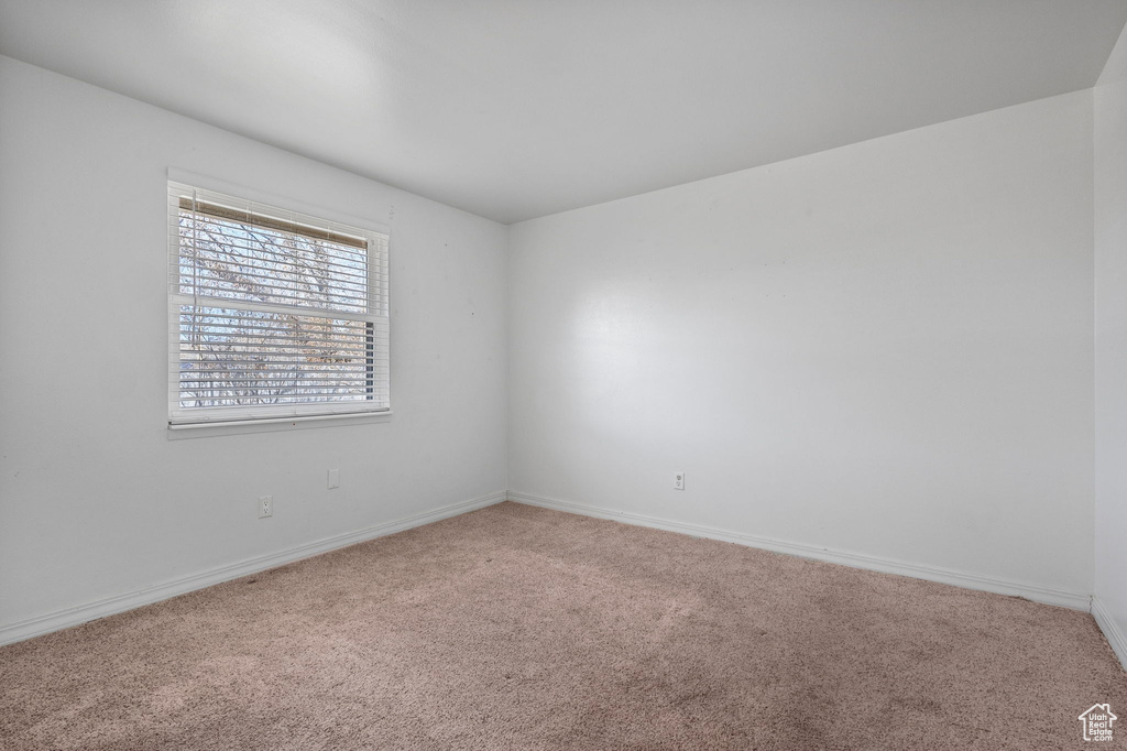 Carpeted spare room featuring baseboards