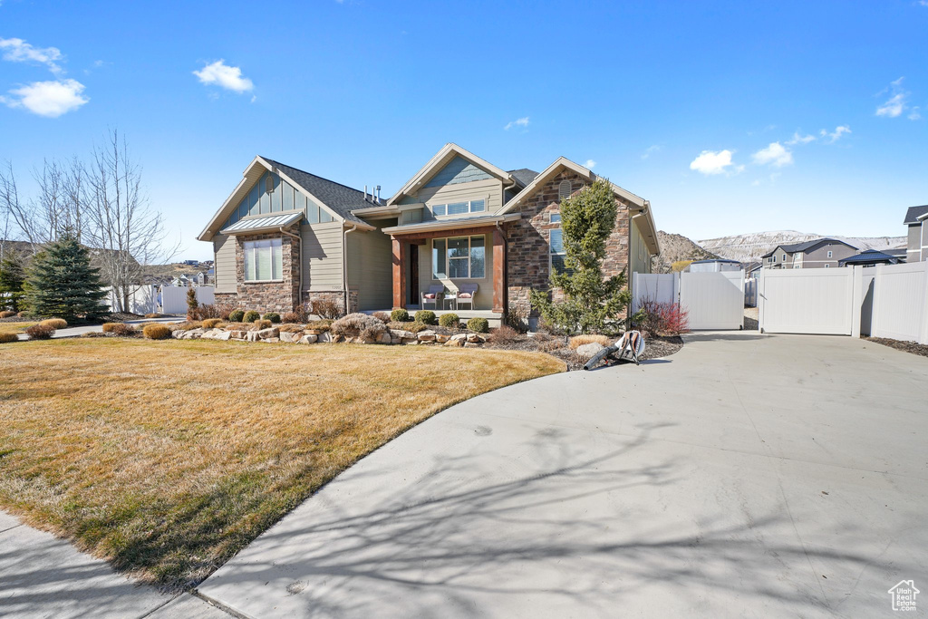 View of front of property featuring a front yard, a gate, fence, stone siding, and board and batten siding