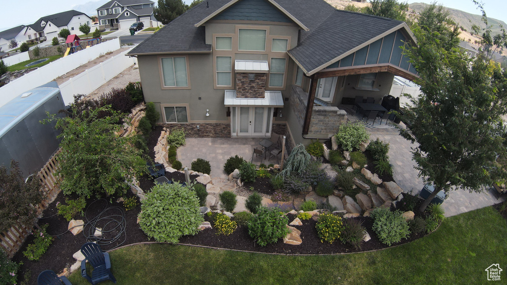 View of front of house featuring stone siding, a patio, stucco siding, and roof with shingles