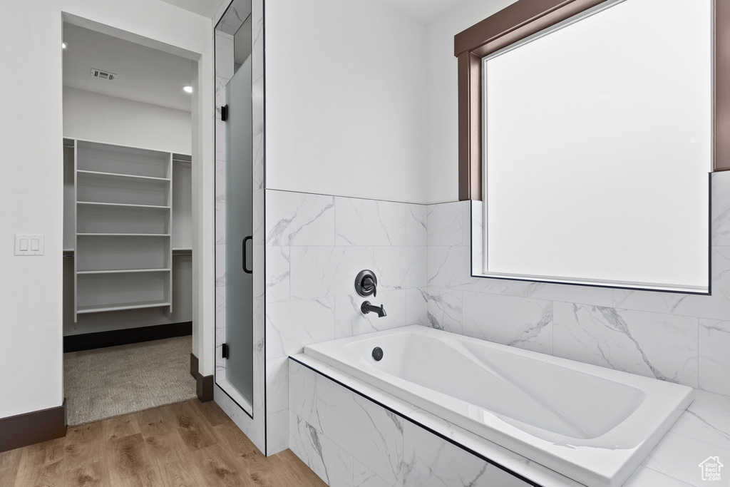 Full bathroom with a shower stall, a bath, wood finished floors, and visible vents